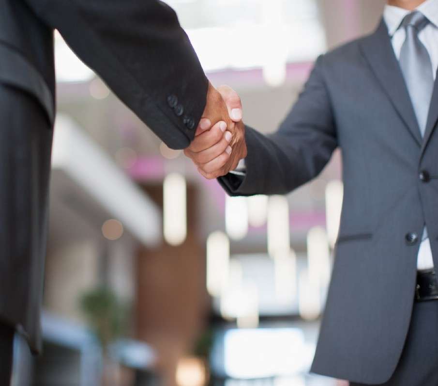 Business professionals shaking hands in an office setting.