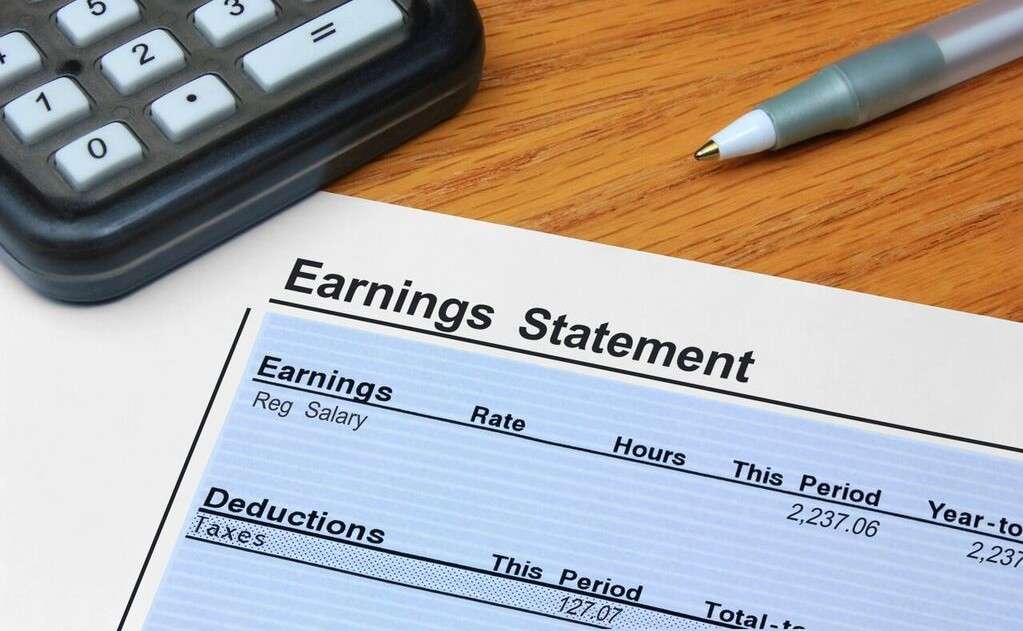Hands working on a calculator and payroll documents
