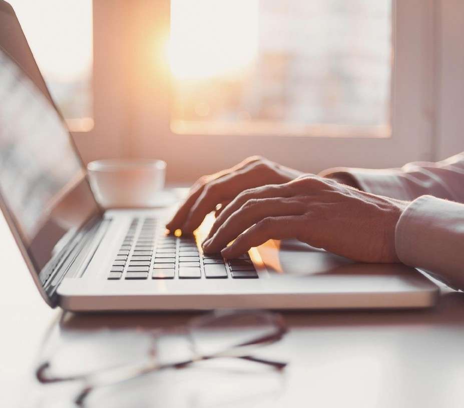 Close up of a person using a laptop with charts on screen.